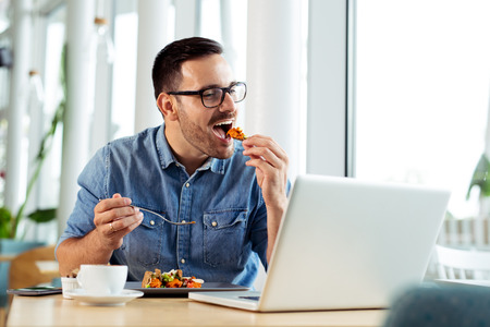 Cheerful businessman eating food in restaurant