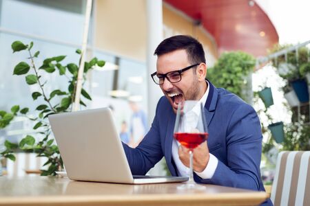 Handsome businessman using laptop at city cafeの写真素材