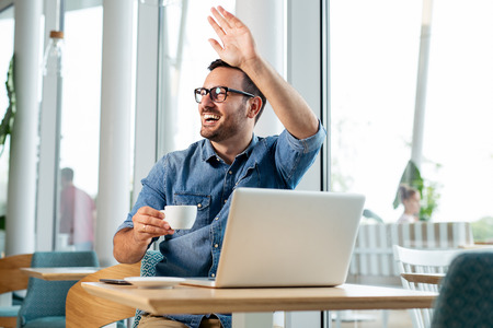 Young attractive businessman drinking coffee and looking at his computer.の写真素材