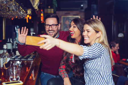 Three friends taking selfie in a bar. - Imageの写真素材