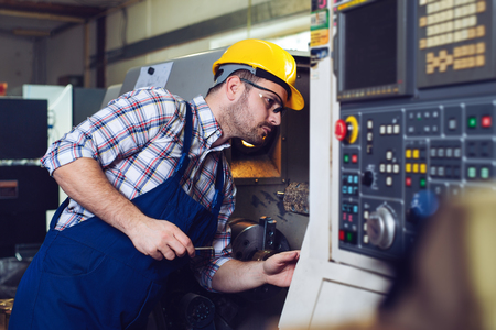 Industrial worker operating cnc turning machine in metal machining industryの写真素材