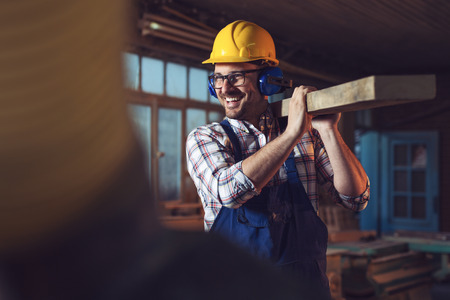 Younger carpenter holds wooden planksの写真素材