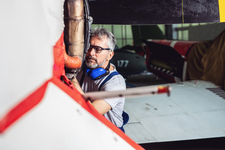 Aircraft mechanic inspects and checks the technology of a jet in a hangar at the airportの写真素材