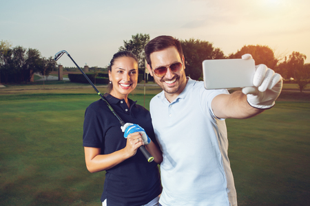 Young couple making selfie on a golf courseの写真素材