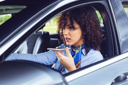The business woman sits in the car and speaks by phone