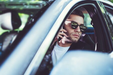 Businessman in car reading message on smartphone