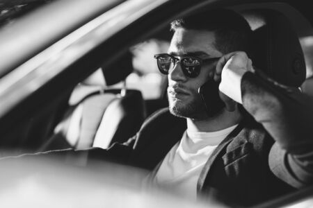 Handsome businessman using mobile phone in carの写真素材