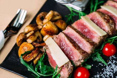 Sliced grilled beef barbecue steak and salad with tomatoes and arugulaの写真素材