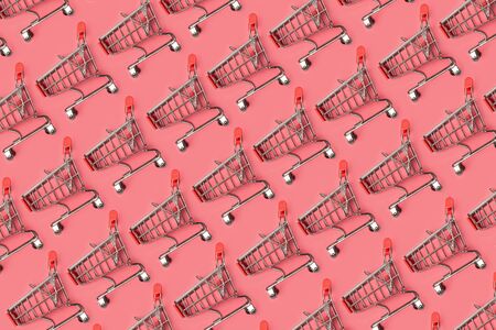 Small empty shopping carts perform a pattern on a pastel colored paper background. Modern trendy design for any purposes.の写真素材