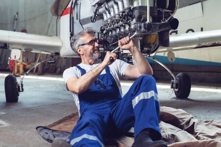 Aircraft mechanic repairs an aircraft engine in an airport hangarの写真素材