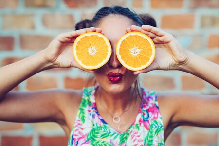 Happy young woman holding oranges halvesの写真素材