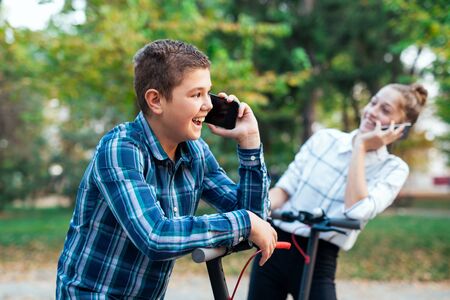 Couple of teenagers wearing plaid shirts talking on a phone.の写真素材