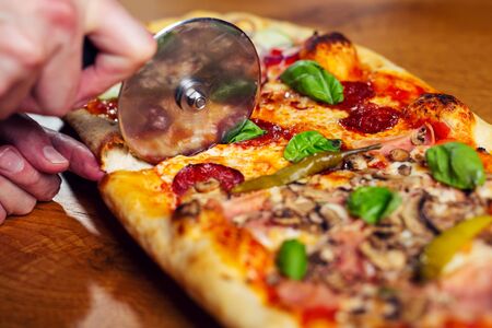 Chef cuts freshly prepared pizza slices.の写真素材