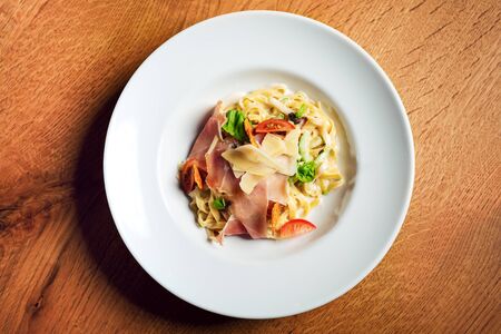 Potato gnocchi pasta with cheese sauce ham and basil on a plate.の写真素材