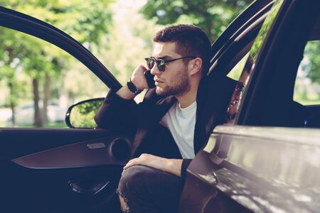 Young attractive man using mobile phone in his carの写真素材