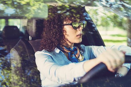Beautiful woman driving car, attractive girl sitting in automobile.