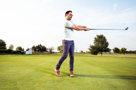 Man playing golf on a golf course in the sunの写真素材