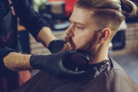 The process of creating a hairstyle and styling a beard for men. A man in a barbershop.の写真素材