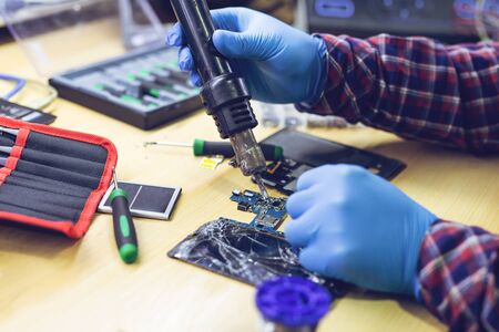 Technician repairing the smartphone's motherboard in the lab. Showing process of mobile phone repair.の写真素材