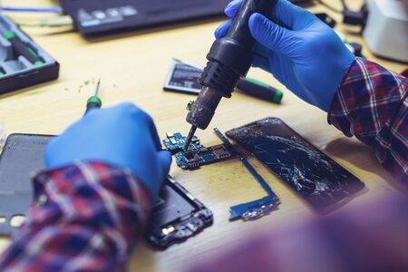 Technician repairing the smartphone's motherboard in the lab. Showing process of mobile phone repair.の写真素材
