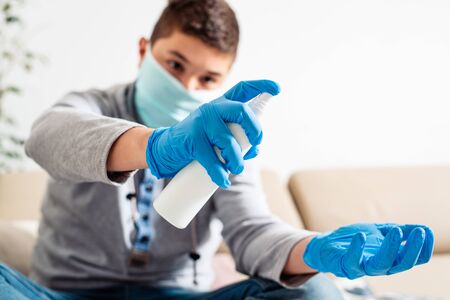 Boy in a medical mask holds a disinfectant in his hands an antiseptic for hands. COVID-19 disinfects hands.の写真素材