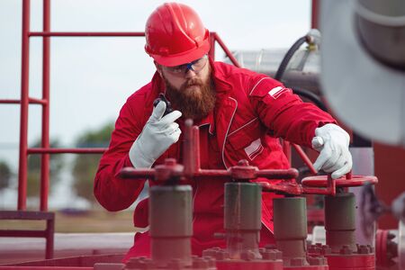 Pipeline engineer making call while inspecting oil and gas equipment.