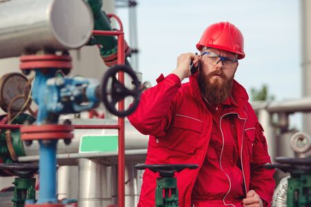 Pipeline engineer making call while inspecting oil and gas equipment.