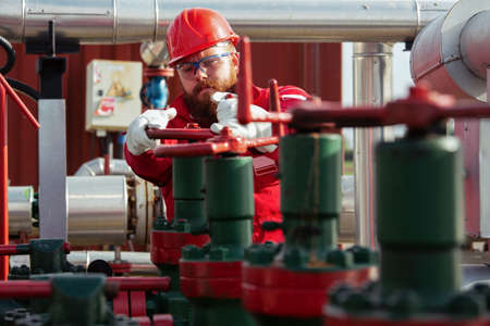 Oil worker turning valve on oil rig