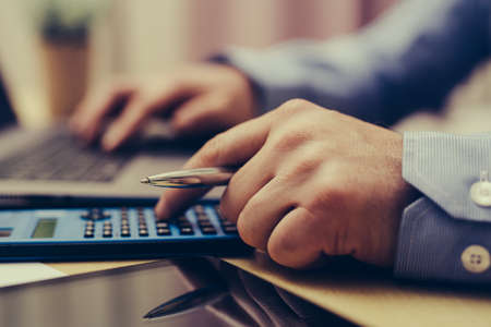 Man using calculator and calculate bills in home office