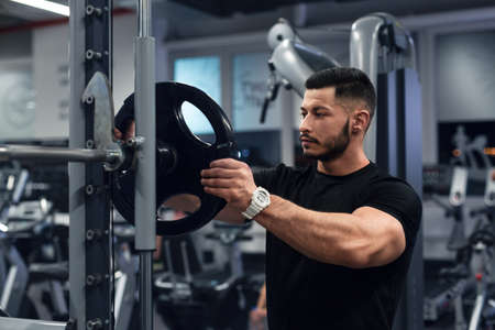 Muscular man working out in gym doing exercises at triceps
