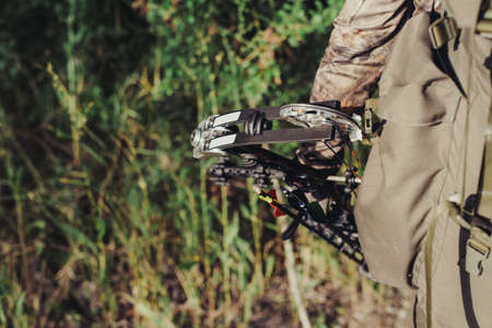 Close up shot of a hunter dressed in camouflage clothing holding a modern bow.の写真素材