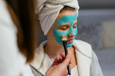 Teenage girl with brush applying clay mask to faceの写真素材
