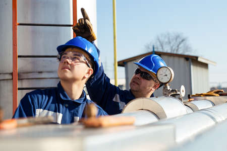 Two Factory worker in a hard hat on Heavy equipment and pipeline