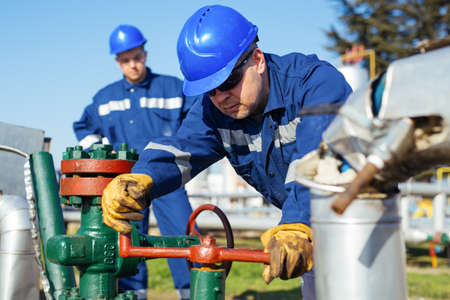 Two Factory worker in a hard hat on Heavy equipment and pipelineの写真素材