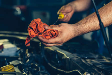 Car mechanic checking oil level in a mechanical workshopの写真素材