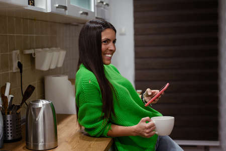 Woman drinking a glass of wine in a modern kitchenの写真素材