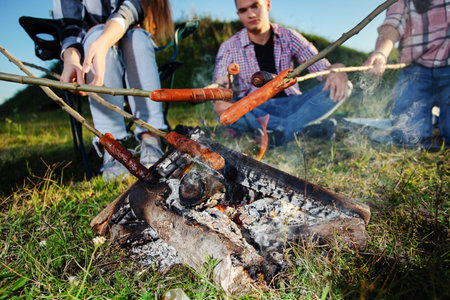 Friends barbecue sausages on camping outdoorsの写真素材
