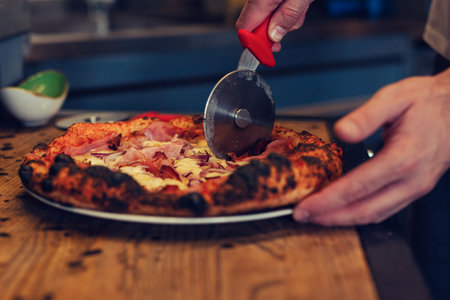 Pizza being cut by pizza cutter. Close up of crust and pizzaの写真素材
