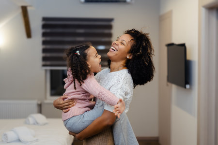 Smiling young African American woman holding in arms small daughter.の写真素材