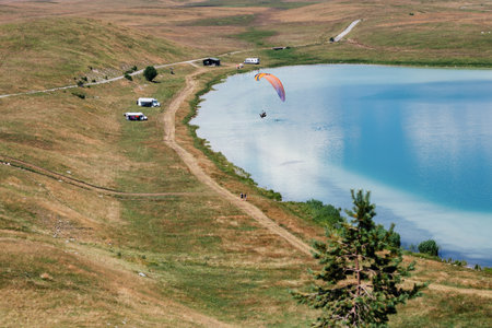Man flying a orange paraglider on the sky with lake backgroundの写真素材