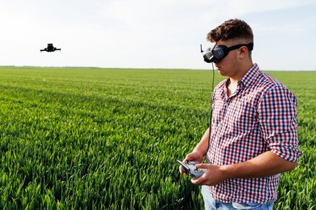 Farmer wearing vr glasses and piloting agricultural drone for inspecting crops in a wheat fieldの写真素材