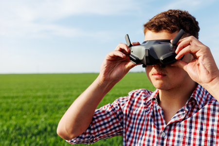Farmer using drone goggles operating an unmanned aerial vehicle in a green field for precision agricultureの写真素材