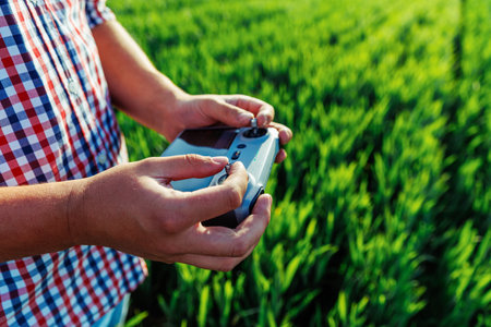 Farmer controlling a drone with remote control in a wheat field, embracing innovative technology for precision agricultureの写真素材