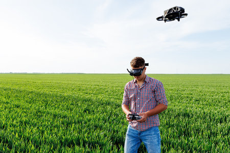 Farmer piloting agricultural drone with remote control and virtual reality headset in wheat fieldの写真素材