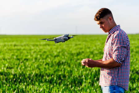Farmer controlling drone flying over wheat field, using modern technology for precision agricultureの写真素材