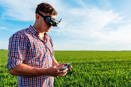 Farmer piloting drone wearing virtual reality glasses in a green field of wheatの写真素材