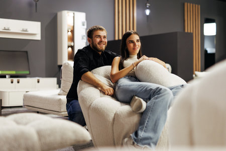 Young couple relaxing on comfortable seating at furniture storeの写真素材