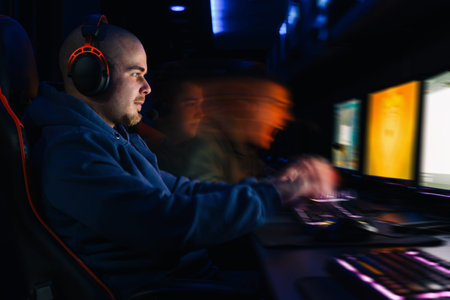 Young man wearing headphones and playing computer games with an intense focus