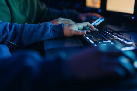 Hands of a person gaming on a computer keyboard with blue and green lighting