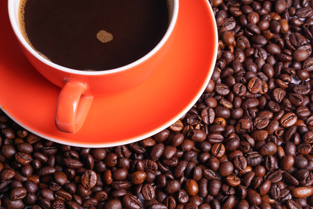 Orange coffee cup on coffee beansの写真素材